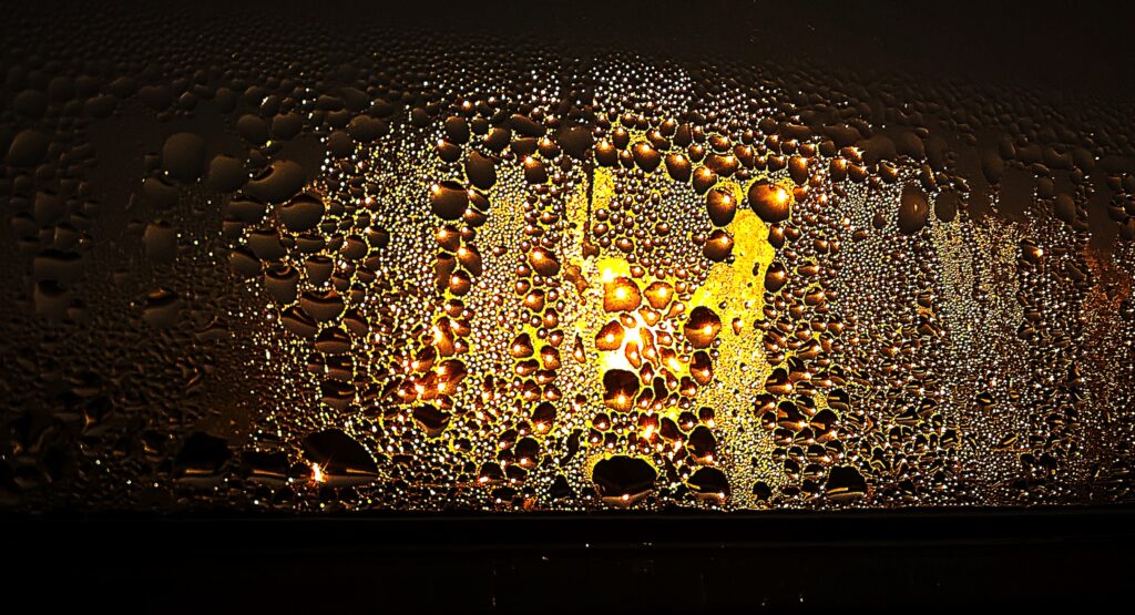Beschlagene Scheibe mit Wassertropfen und Eisblumen am unteren Rand der Dichtung