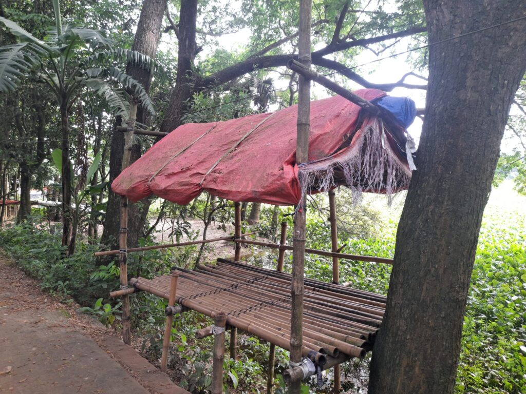 Gespanntes Tarp über einer Kochstelle, an zwei Seiten offen, im Hintergrund ein Zelt